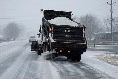 Truck salting roads covered in snow.