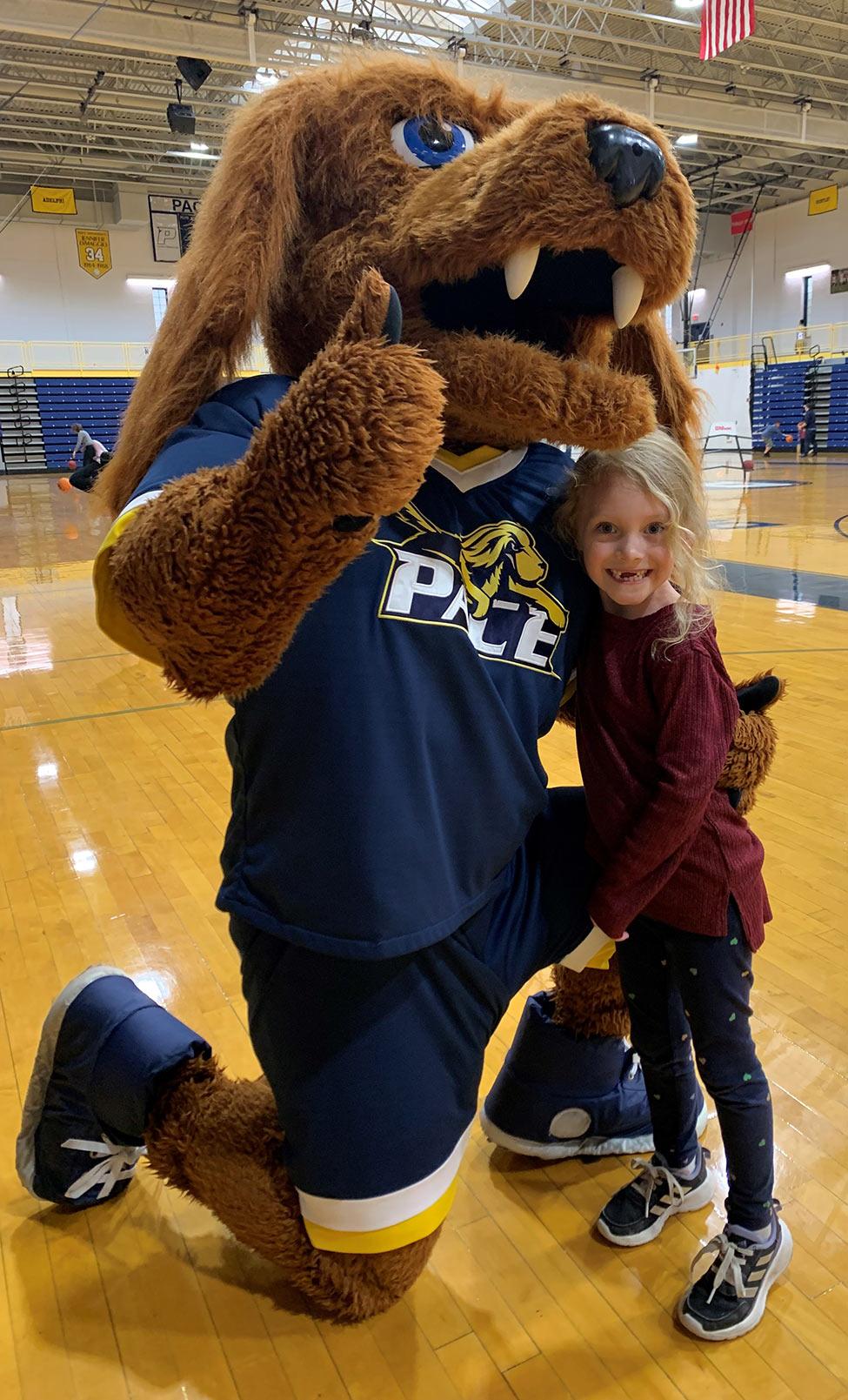 Pace University mascot, T-Bone, posing with a young child
