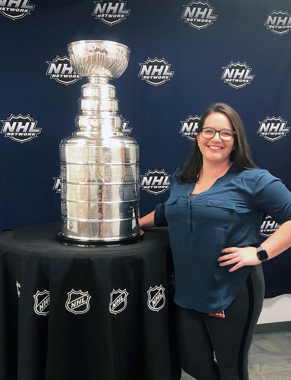 Pace University's Media, Communications, and Visual Arts alum Kelly Writenour posing with the NHL Stanley Cup