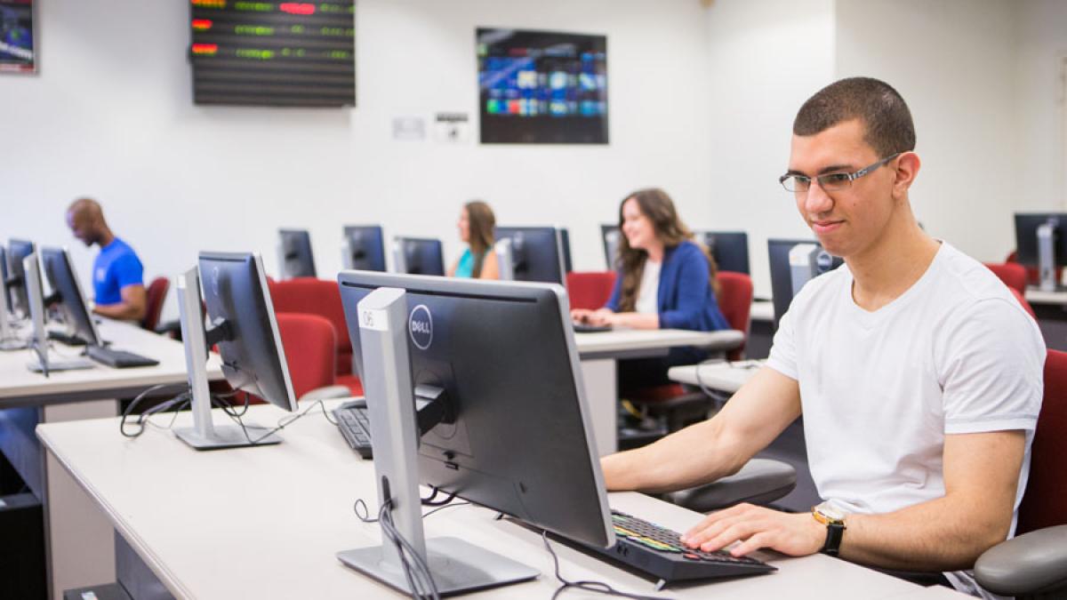 Lubin student sitting at Bloomberg terminal in a classroom at One Pace Plaza on the New York City Campus