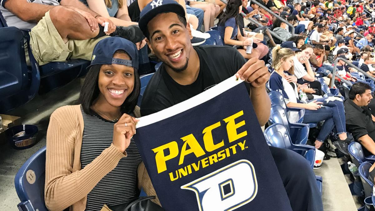 a man and a woman inside yankee stadium holding a pace university penant 