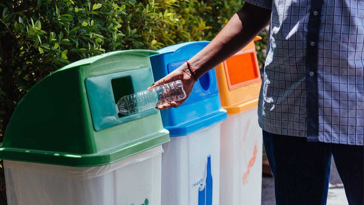 man putting a bottle into a recycling bin