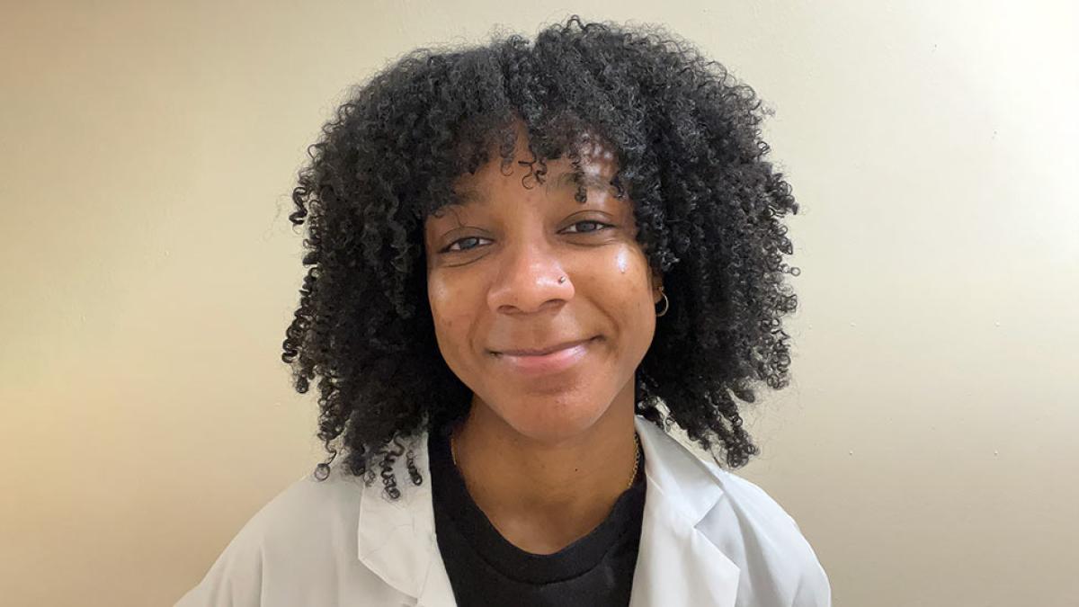 Pace Student Kaylin Smith wears a white coat and smiles