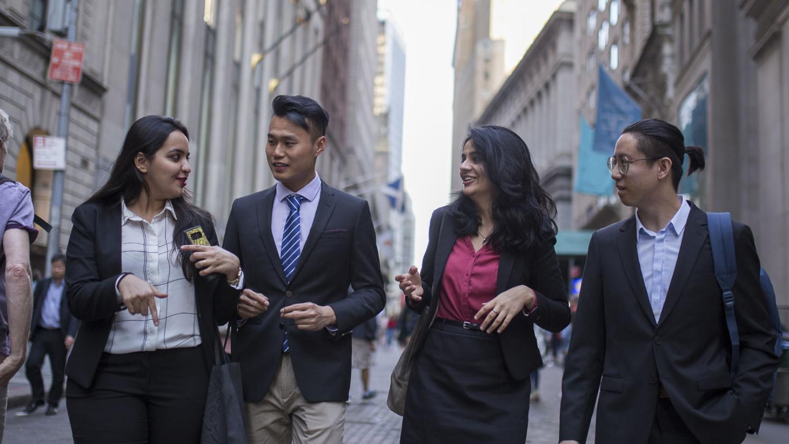four Lubin students in business attire walking in Lower Manhattan near the New York City Campus