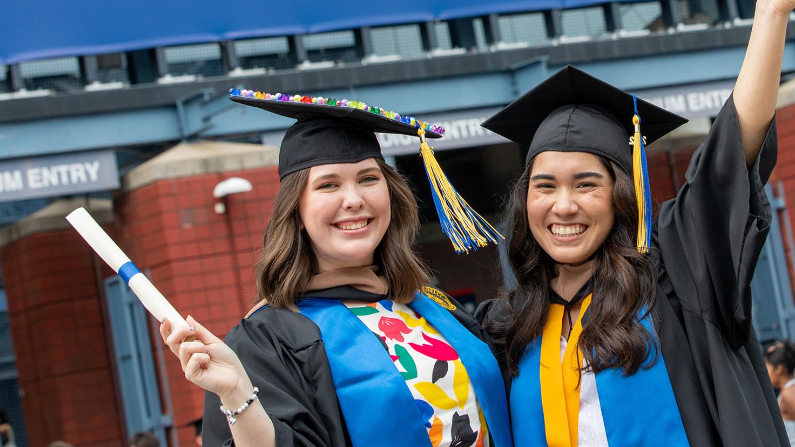 Two students celebrating their Commencement, smiling at the camera.