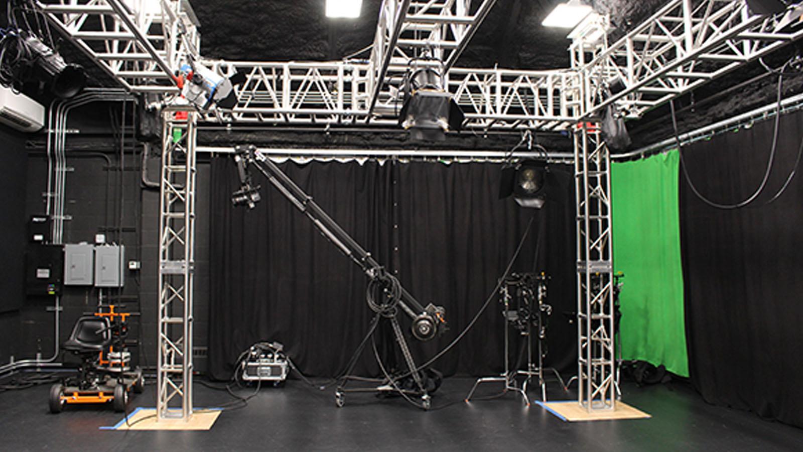 A large production stage with a boom mic, gimble, stage lights, and greenscreen