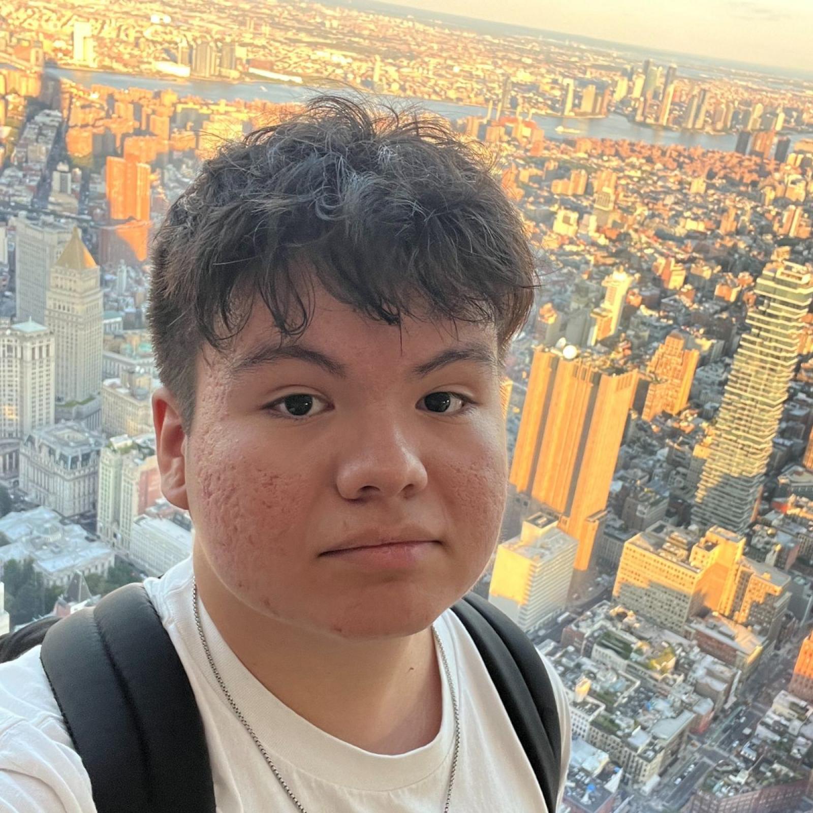 Pace student Daniel Ramos taking a selfie while overlooking the NYC skyline at sunset.