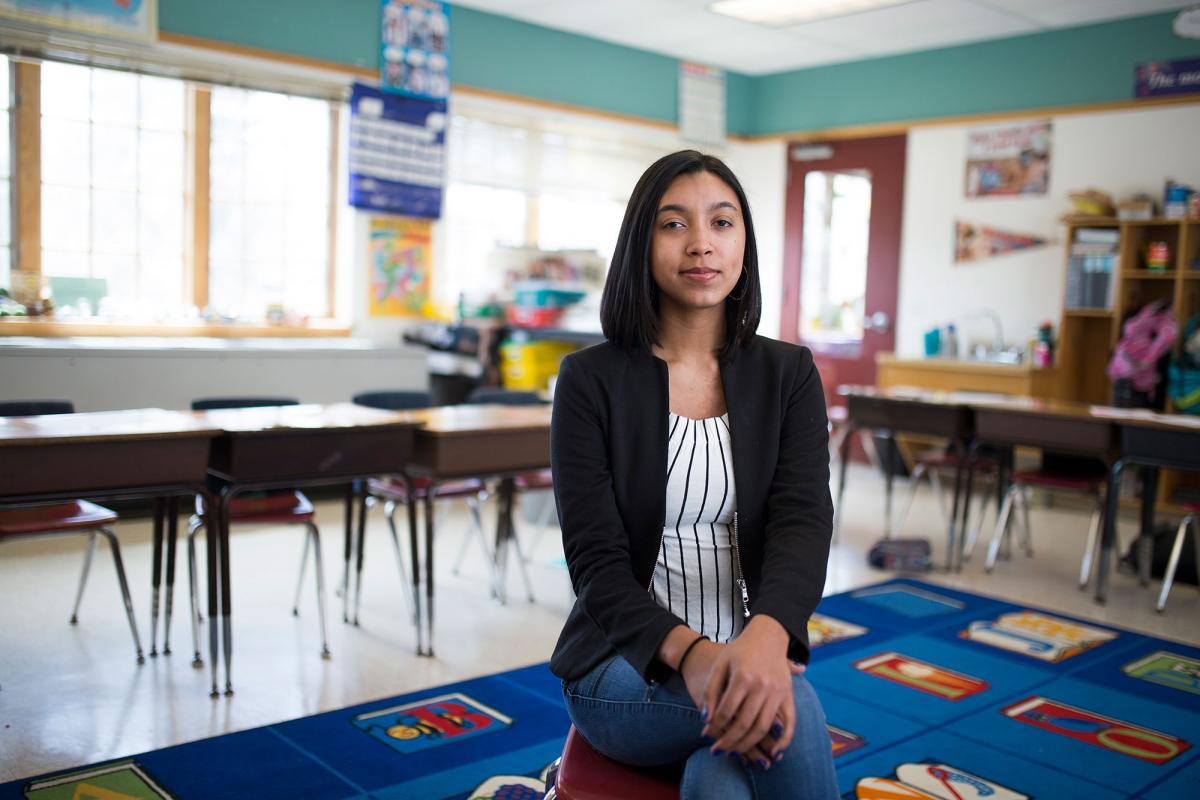 Student sitting in a classroom smiling at the camera.