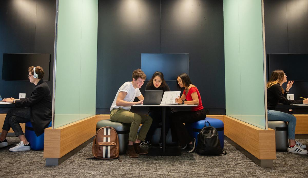 Students sitting at a desk looking at their computers.