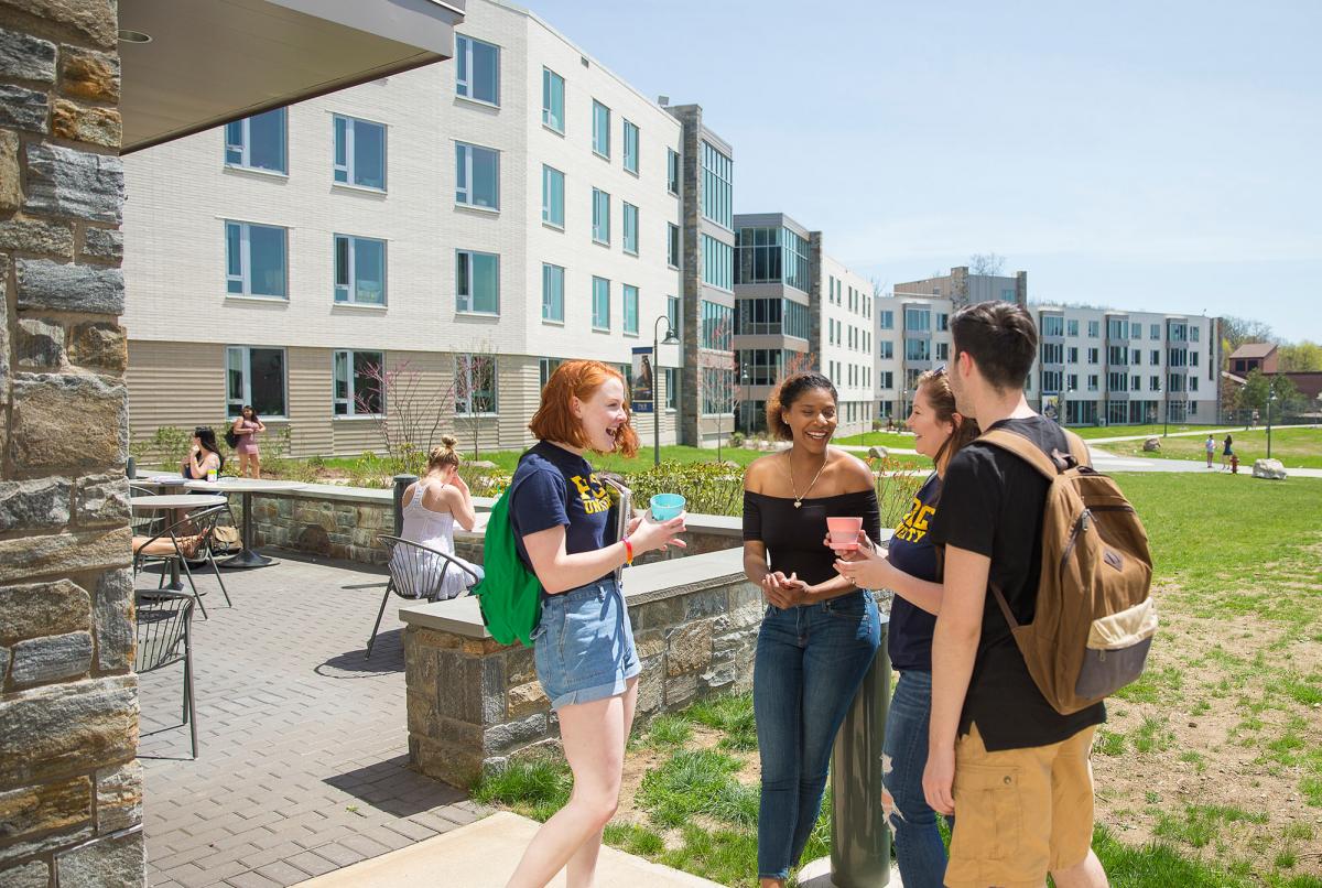 Group of students standing in front of one of the residence halls on the Westchester campus.
