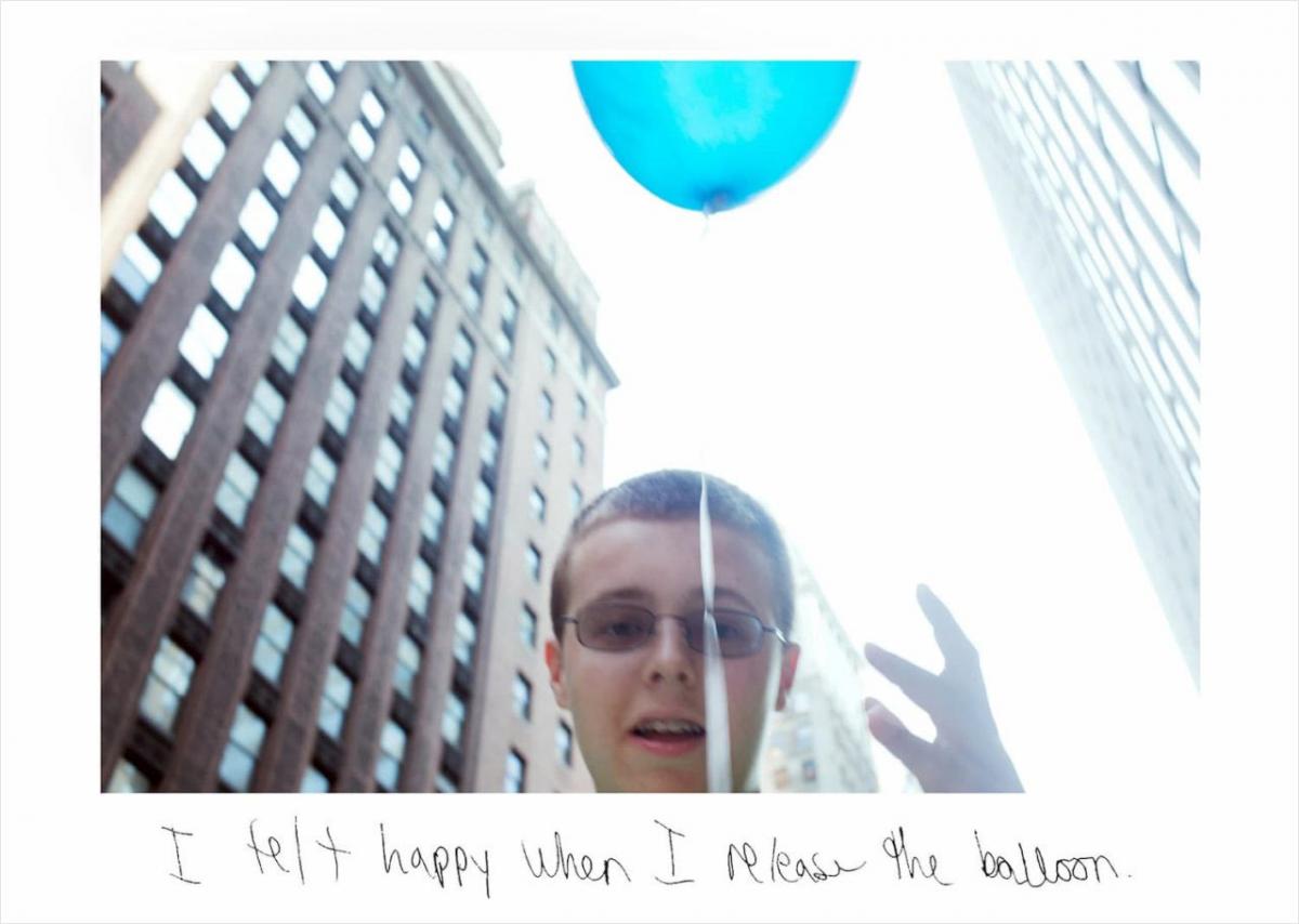 boy releasing a baloon into the New York City skyline.