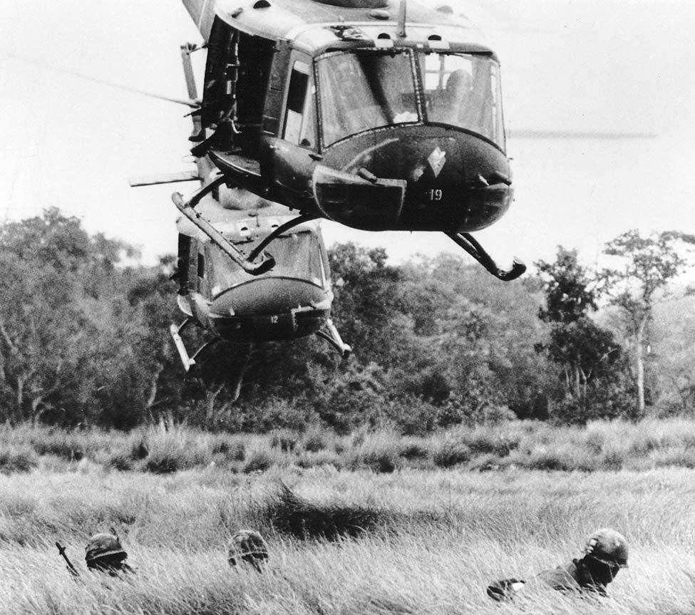 black and white photo of a Vietnam war era helicopter flying low to the ground