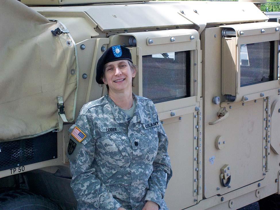 Avery Leider, veteran and Pace double alumna, leans against a military vehicle in her uniform