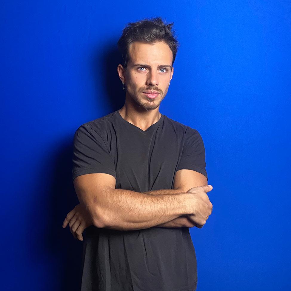 man with arms crossed in front of blue wall