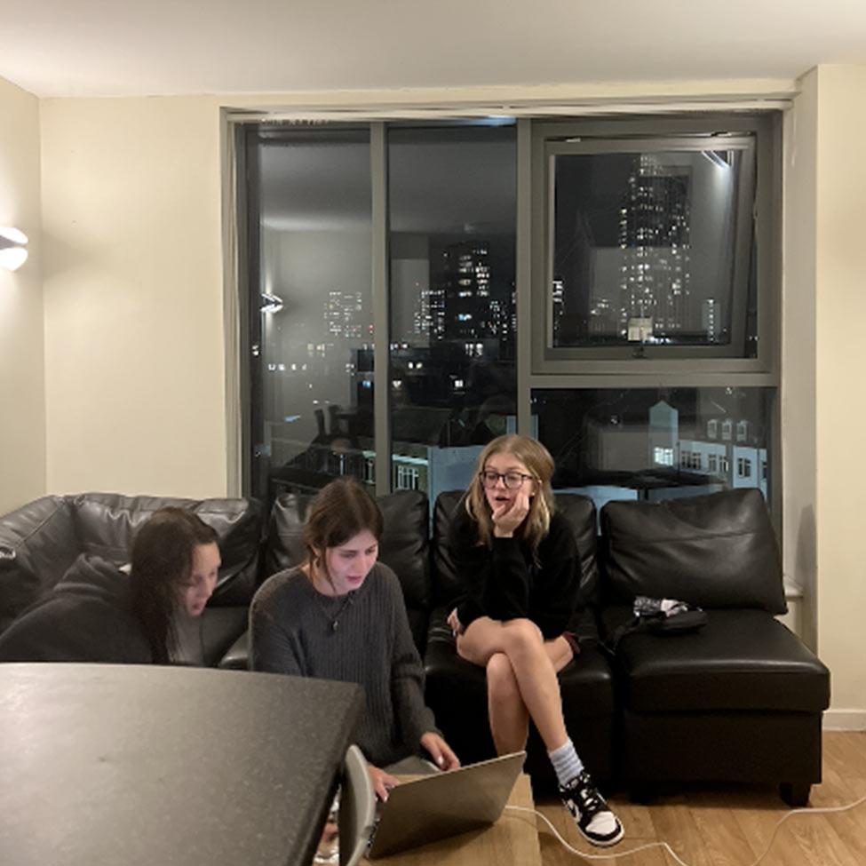 Pace University students looking at laptop in an apartment in London