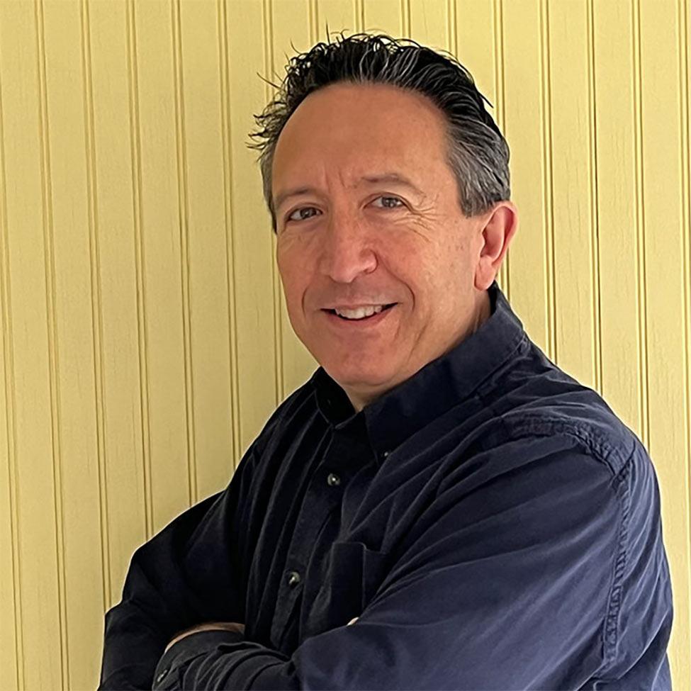 man smiling for camera in front of yellow panel wall