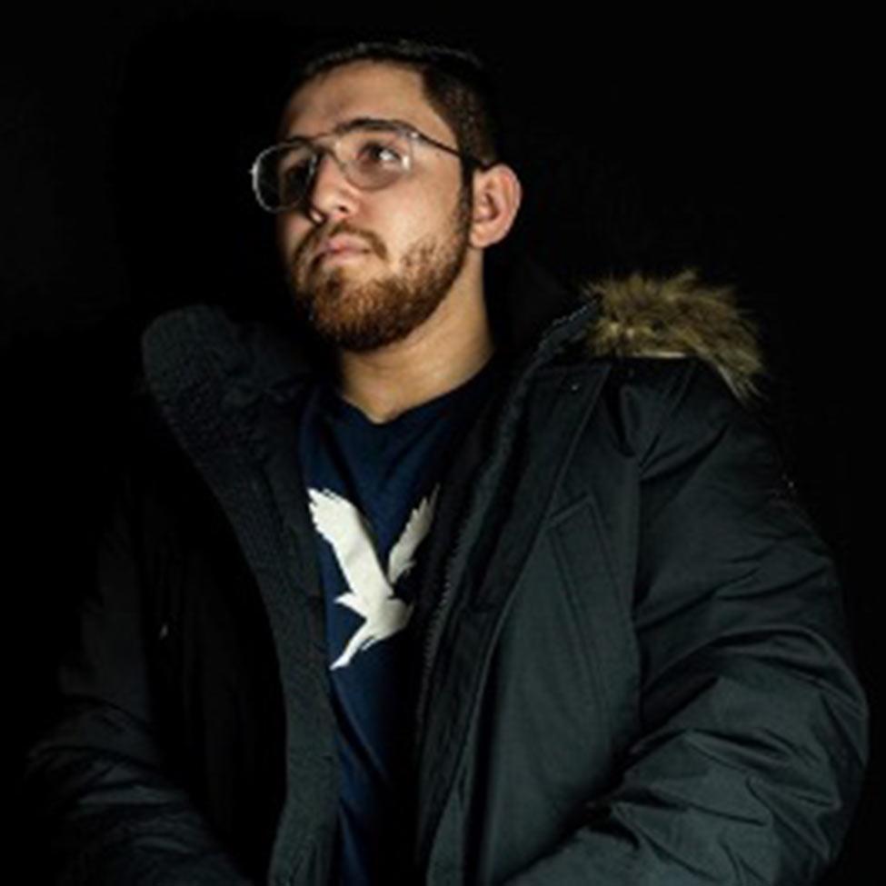 Portrait of Nicolas Lotto wearing a black shirt with a black coat and a black background