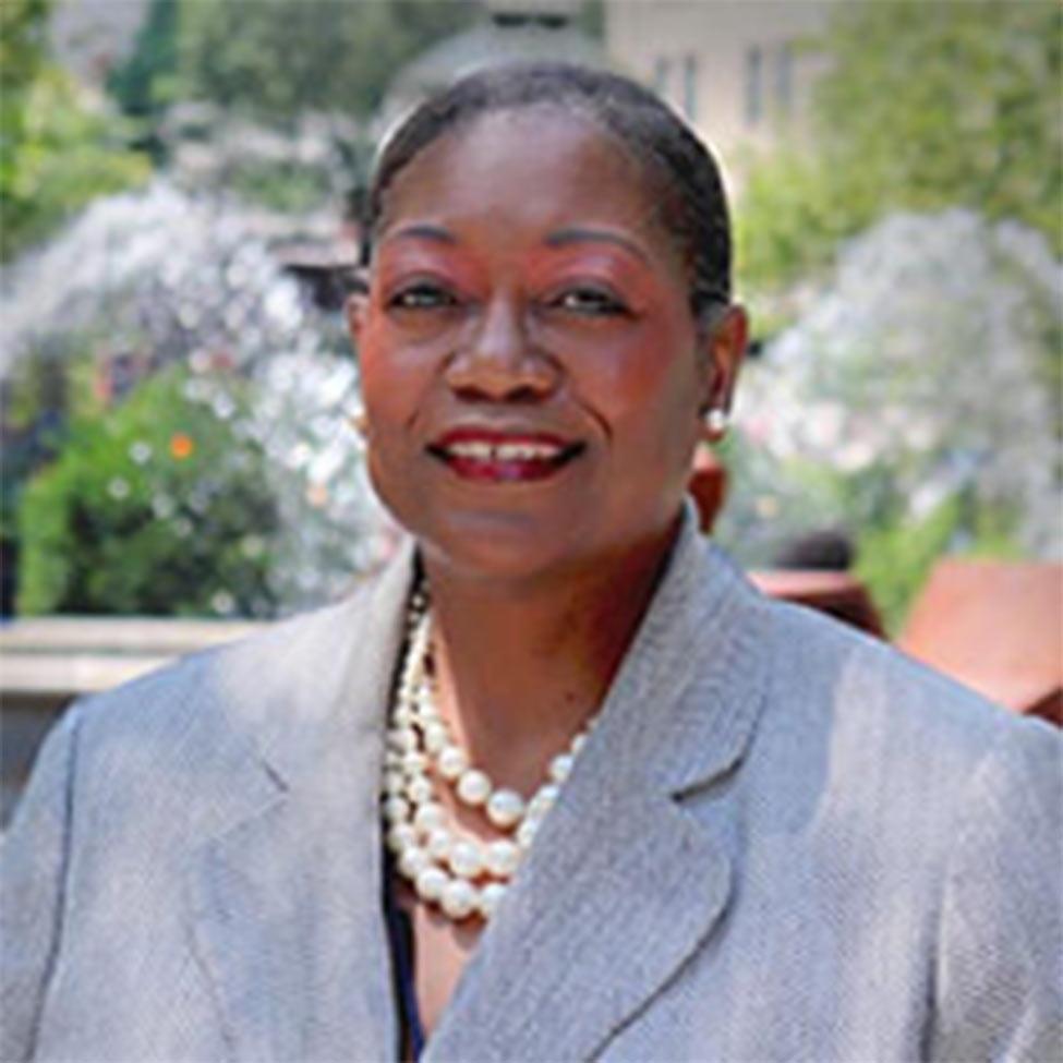 Portrait of Tresmaine Grimes wearing a gray suit jacket with pearl necklaces