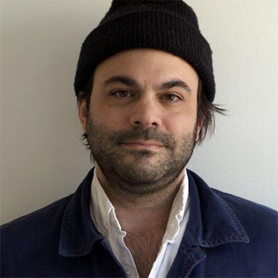 Portrait of Jesse Bonnell wearing a black knitted cap and a dark suit jacket