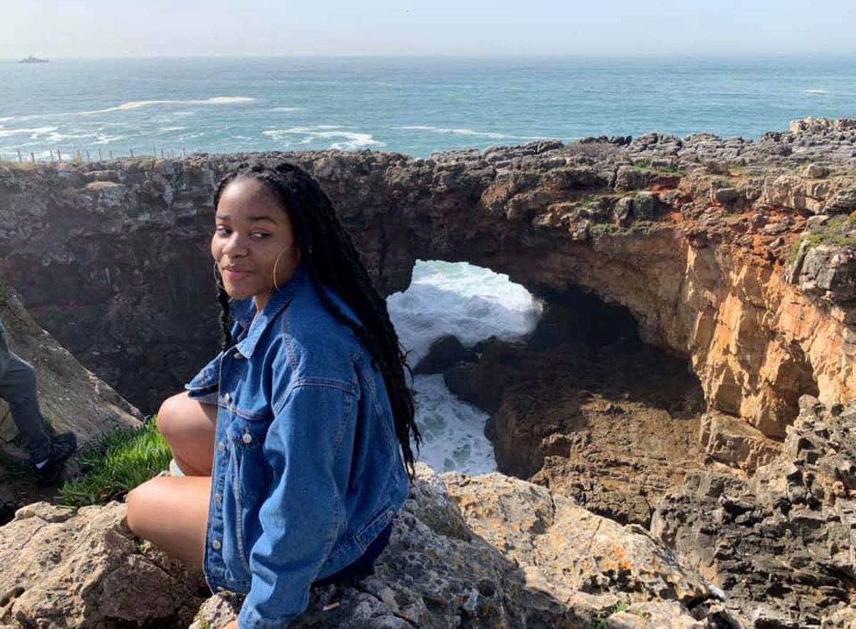 Lubin student Geanina Riley '21 sitting on a cliff over the sea during her semester abroad in France