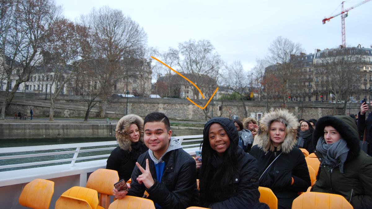 Lubin student Jamie Mathurin '21 sitting on a tram near a river with other students and passengers during her semester abroad in France