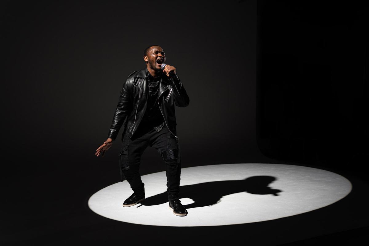 Student from the Pace Performing arts School singing on stage with a spotlight shining down on him.