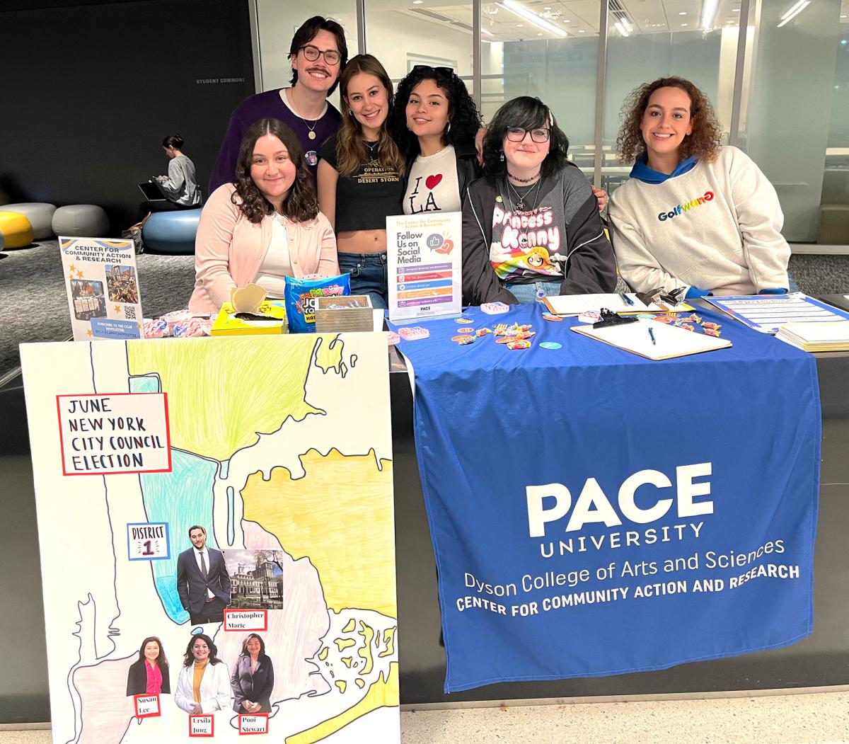 Several students at a table with Center for Community Action and Research materials and a poster of the June City Council Election.