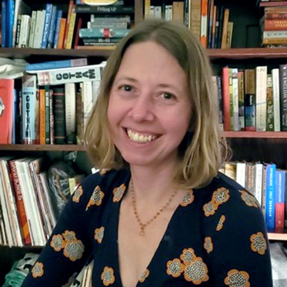 Pace University Associate Professor of English, Kelly Krietz smiling with books behind her