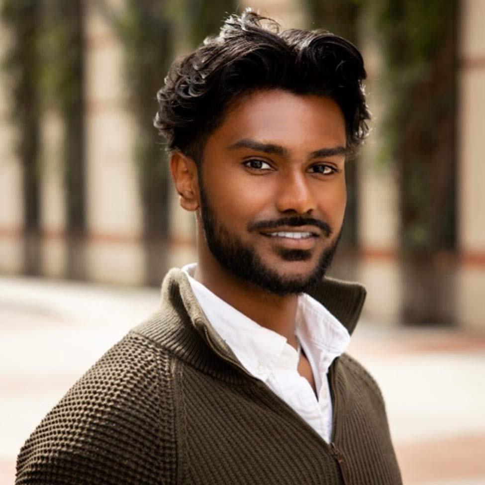 Portrait of Rudra Persuad, young chemistry major alum at Pace University wearing a dark zippered cardigan