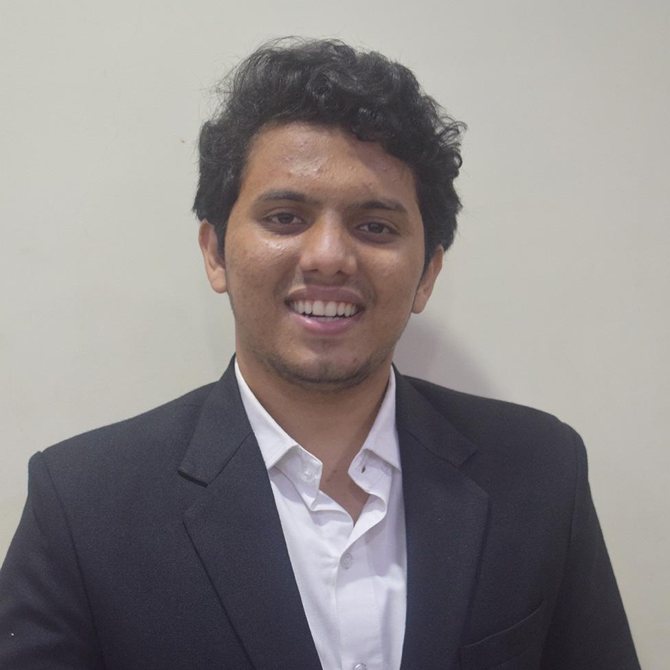 Darsh Joshi wearing a white shirt and blue jacket smiles at the camera