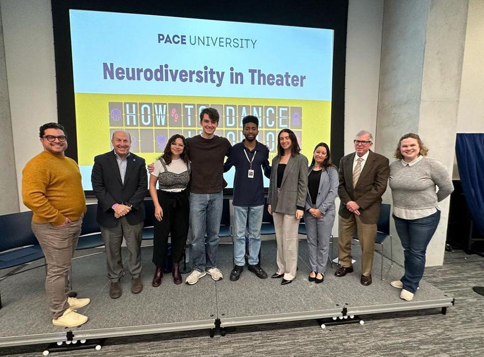 A group of people posing for the camera in front of a screen that says "Neurodiversity in Theater"