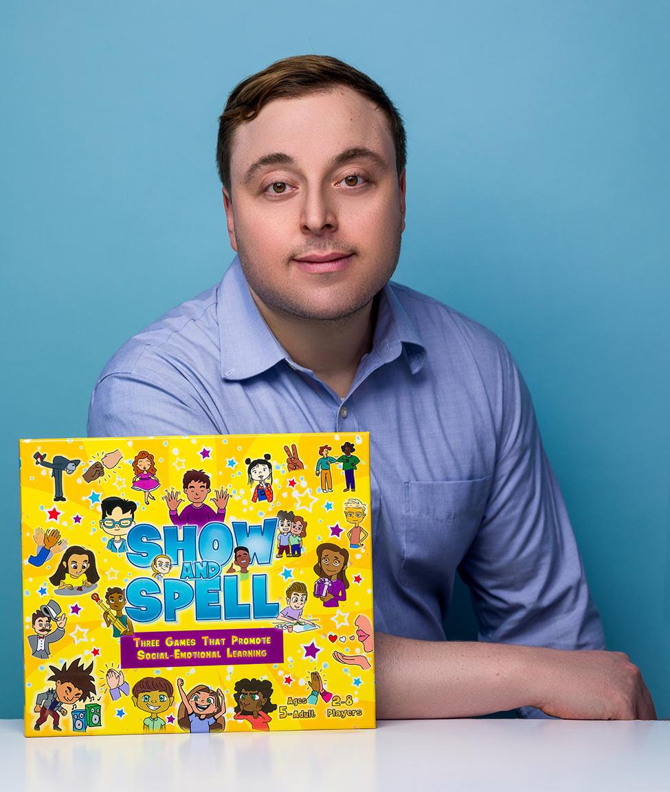 Stan Royzman posing with his board game, Show and Spell.