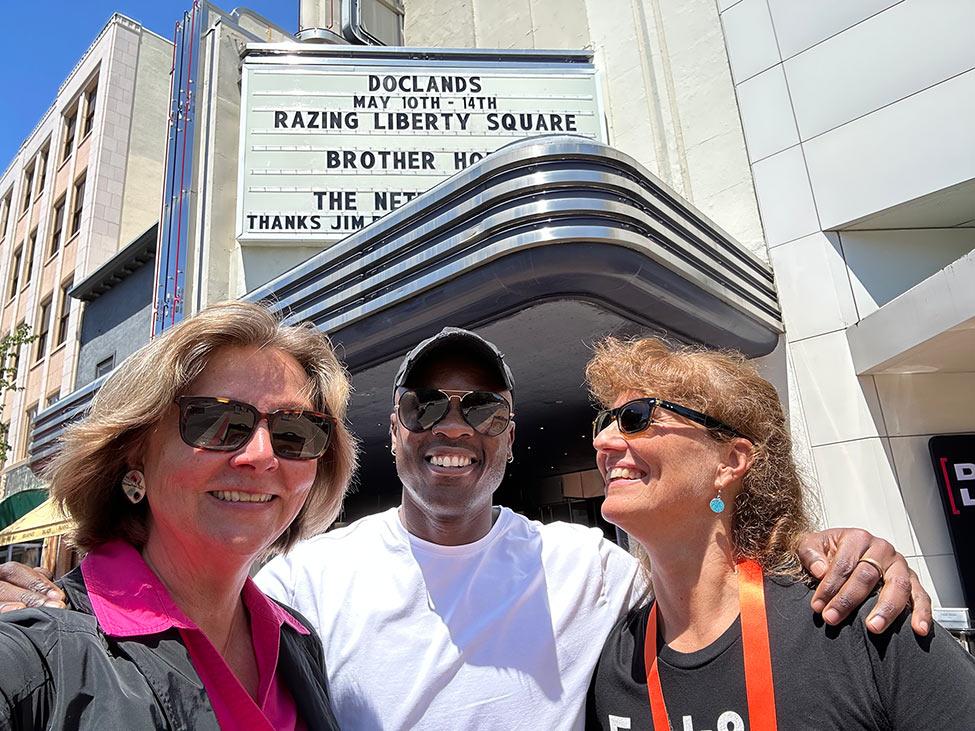 Cronna Sager, Katja Esson, and one of the film protagonists stand outside a theater marquee 