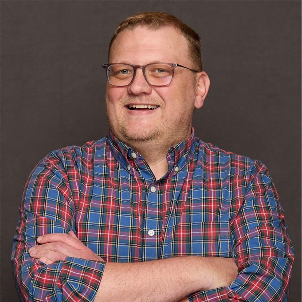 D2L expert Shannon Creighton wears a plaid shirt and crosses his arms