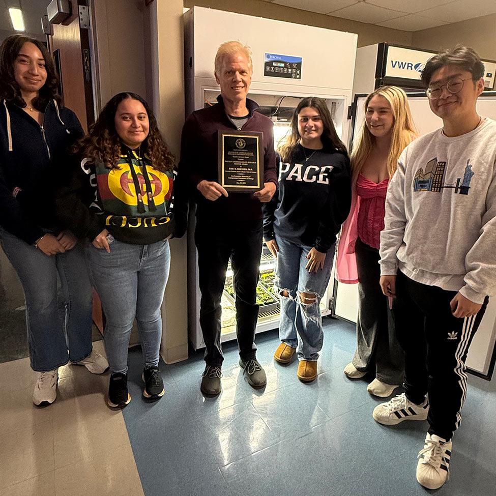 Pace faculty member Eric Brenner holds his award next to his students