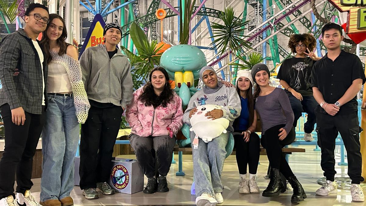 Seidenberg student Daisy Molina sitting on a bench surrounded by her friends.
