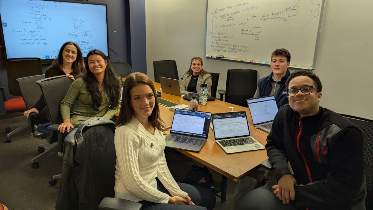 Pace Seidenberg students posing for a photo in a conference room during a hackathon.