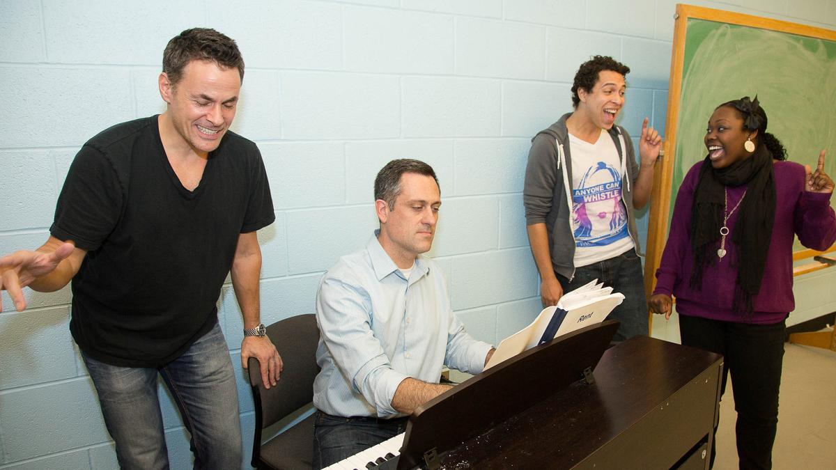 Pace University performing arts students gather around a piano