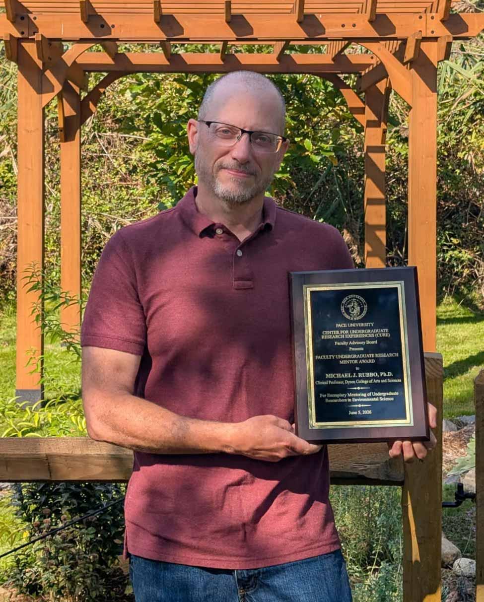 Michael Rubbo posing for a photo with an award placard.