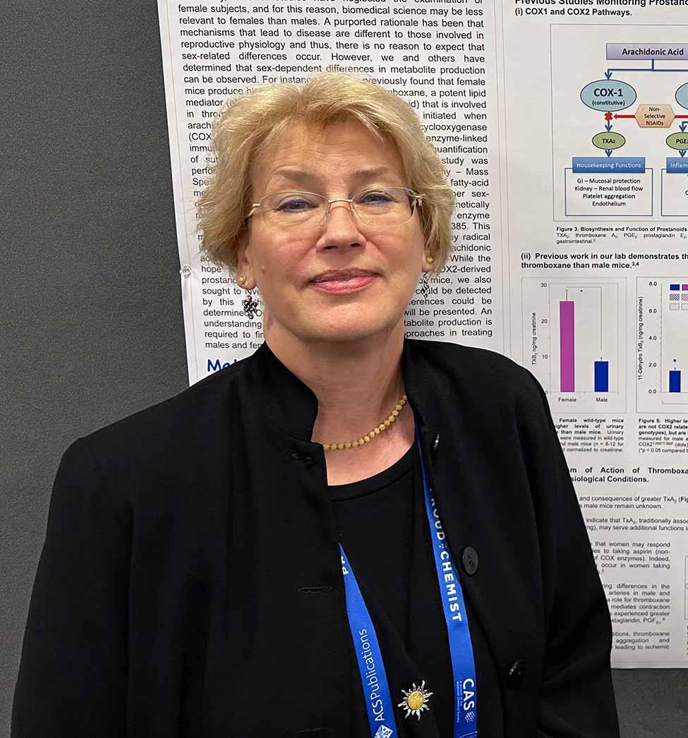 Rita Upmacis posing for the camera in front of an academic poster.
