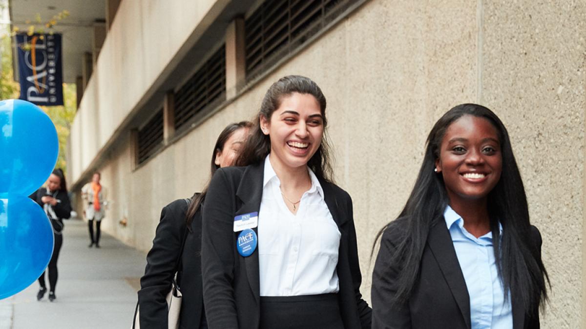 Group of students walking into 1 Pace Plaza dressed in business attire.