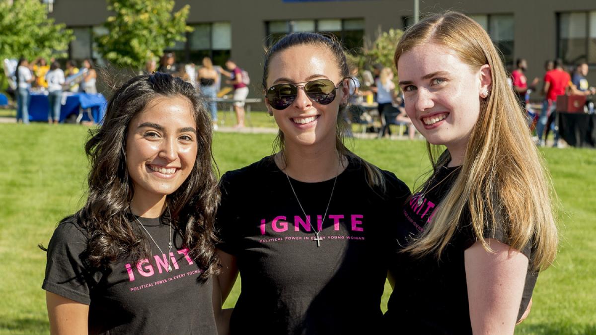 Students smiling at the camera wearing an Ignite shirt.