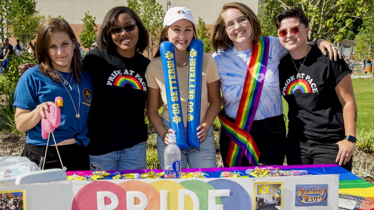 Students smiling at the camera at the Pace Pride table.
