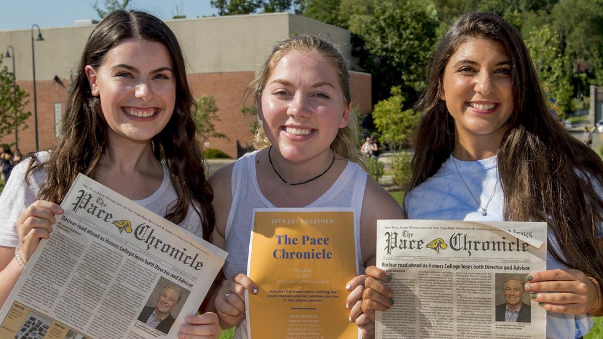 Student holding up samples of the Pace Chronicle newspaper.