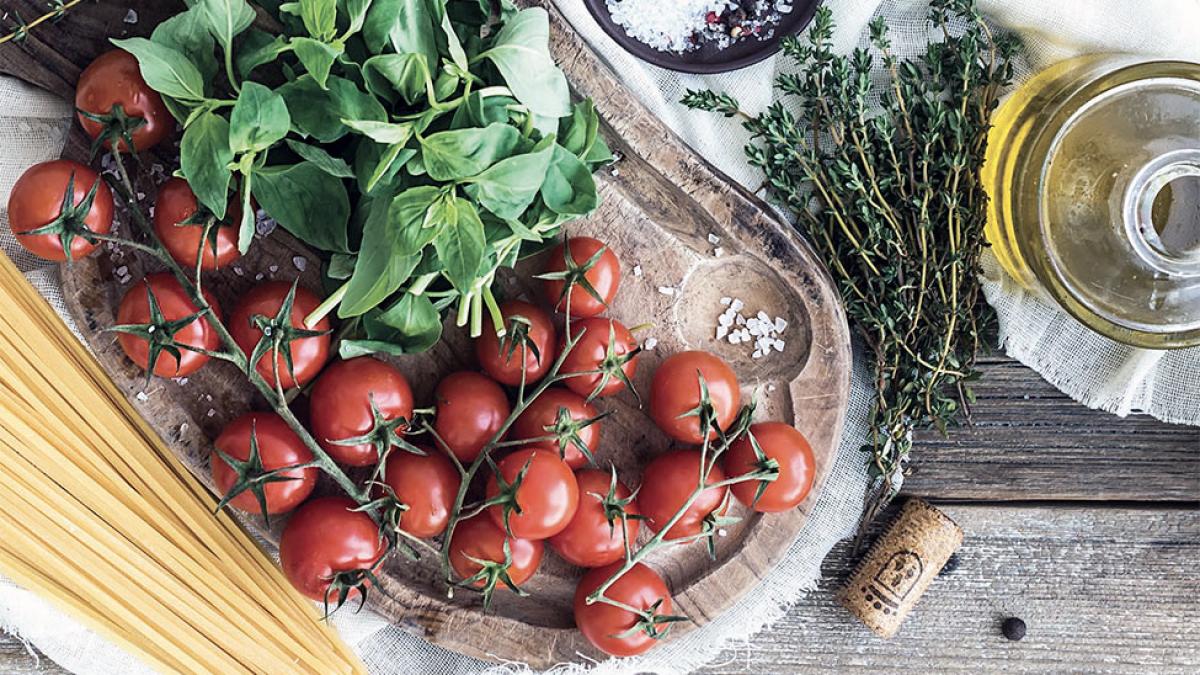 tomatoes, basil, olive oil, and spaghetti on a table.