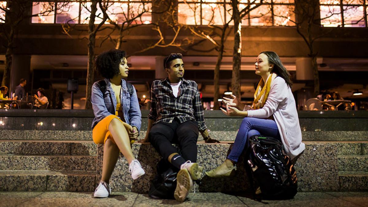 Group of students sitting on some steps in front of 1 Pace Plaza.