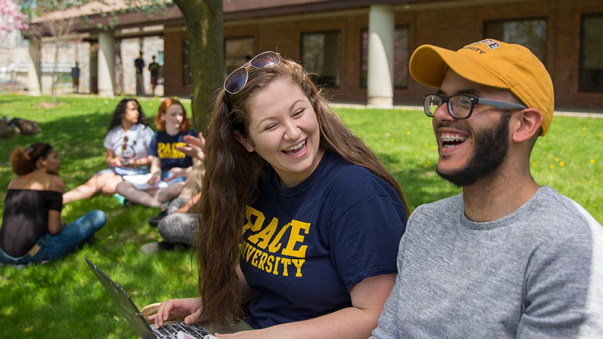 Students sitting on a bench in front of the library on the Westchester campus.