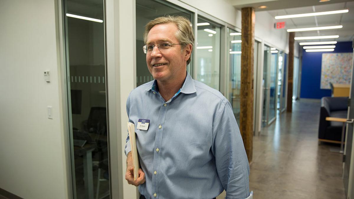 Staff member walking with an employee ID attached to his shirt.