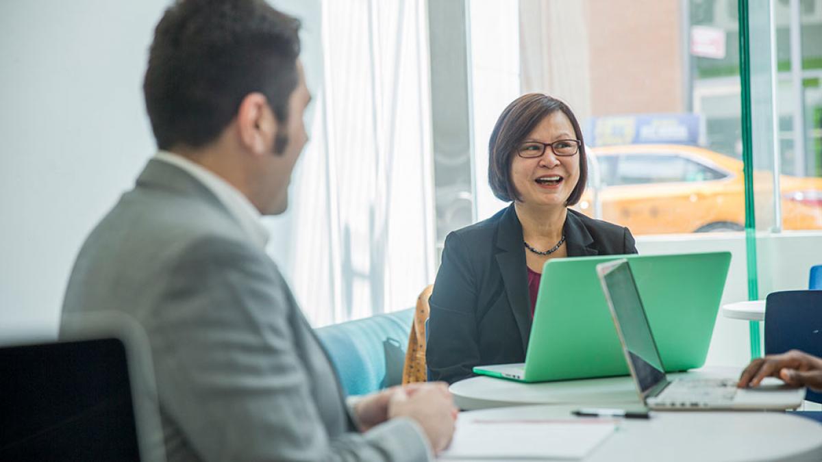 Staff member smiling at the camera while sitting in front of a computer.