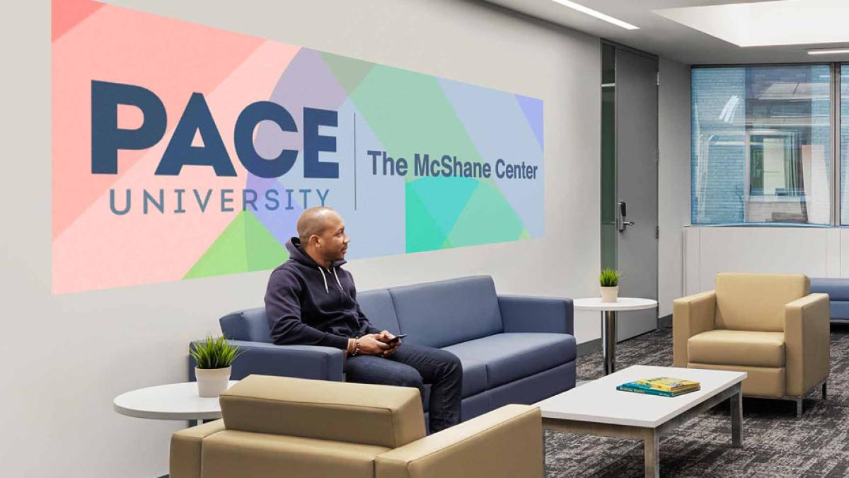 Room with The McShane Center banner and African American student sitting on couch infront of it